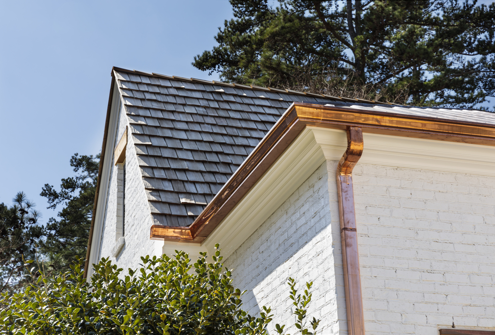 A white building with a grey roof and copper gutters.