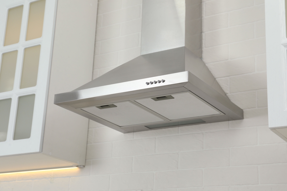 A metal range hood in a white kitchen.