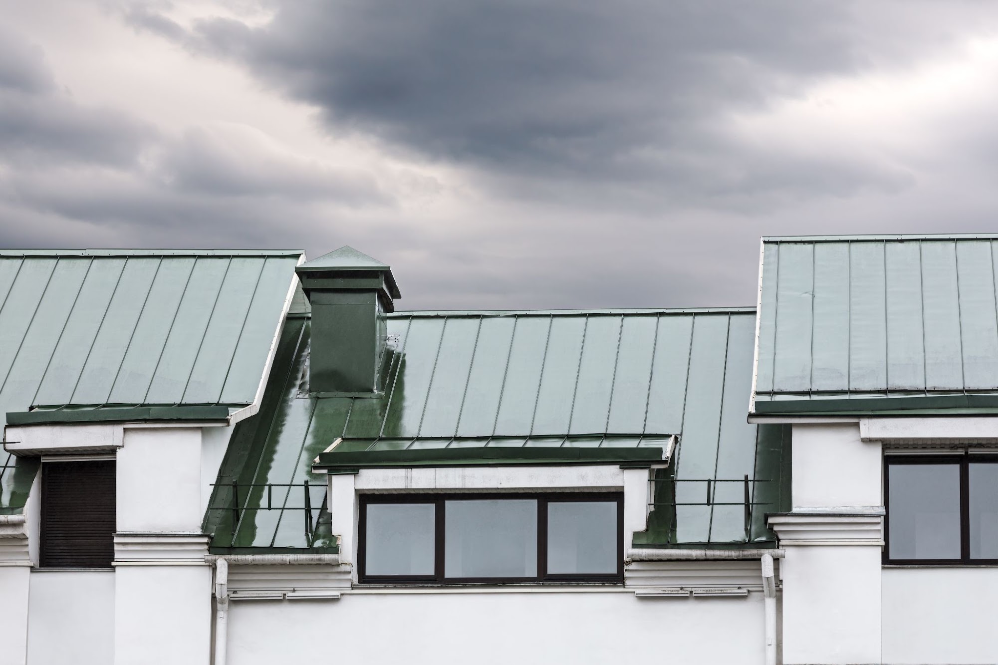 Standing seam metal roof on a building under dark storm clouds
