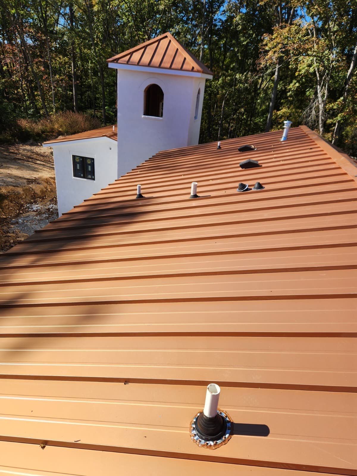 Copper Penny standing seam roof and tower roof on a white stucco home